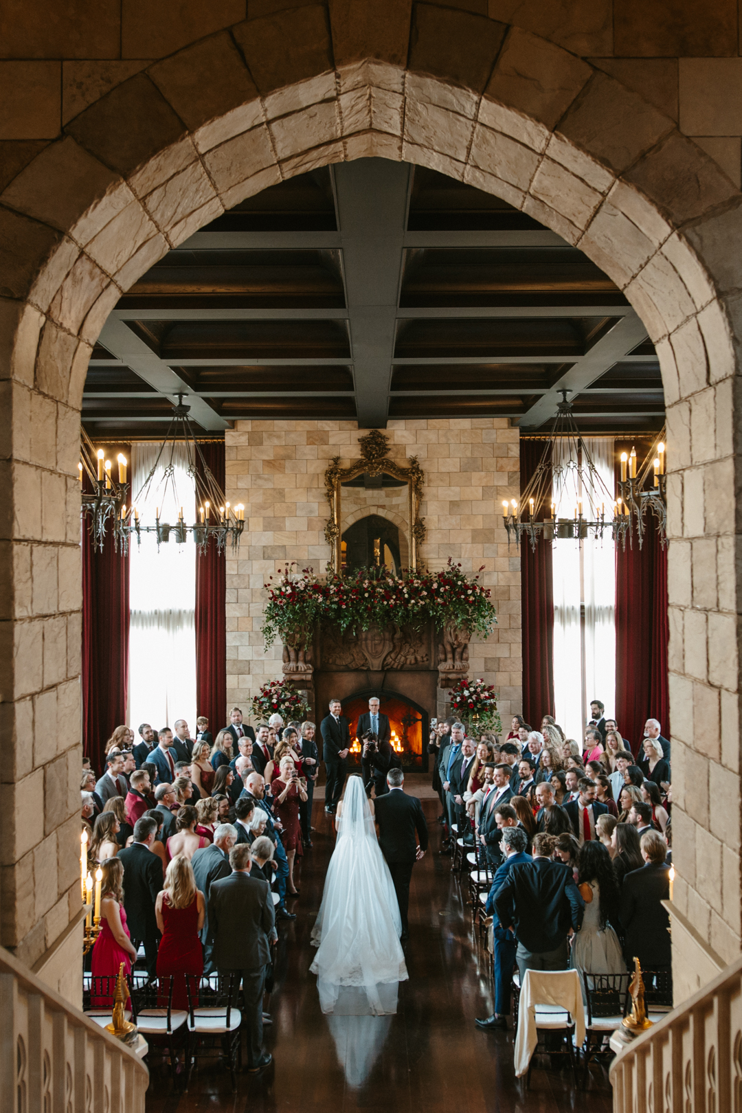 Bride walking down the aisle under a stone archway at a candlelit Virginia wedding ceremony, photographed by Eternally Yours